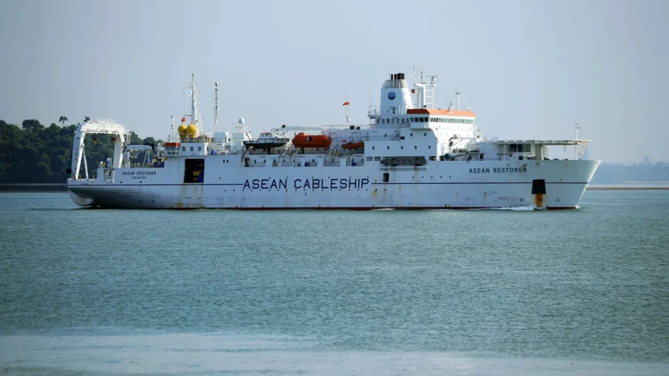 A cable ship named ASEAN Restorer navigating in clear ocean waters, highlighting maritime technology.
