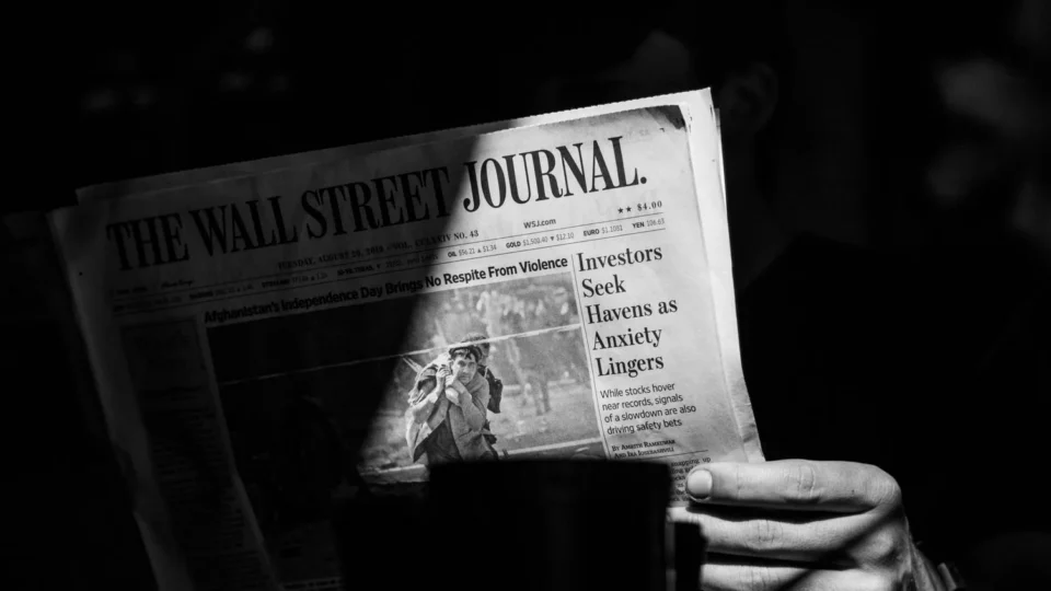 A monochrome photograph capturing a person reading The Wall Street Journal.