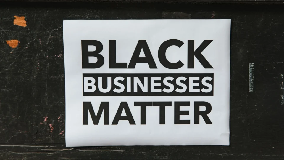 A poster advocating support for Black-owned businesses displayed on a textured wall.