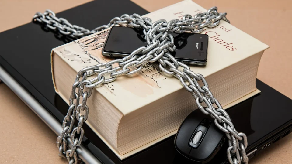 Chain-locked book, phone, and laptop symbolizing digital and intellectual security.
