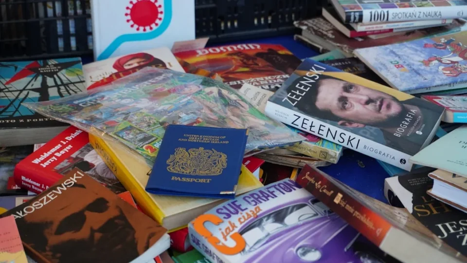 A cluttered pile of various books and a blue passport.
