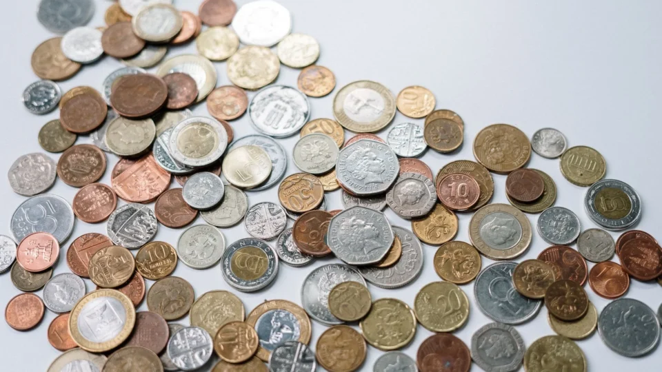 A variety of international coins scattered on a light background, showcasing different currencies.