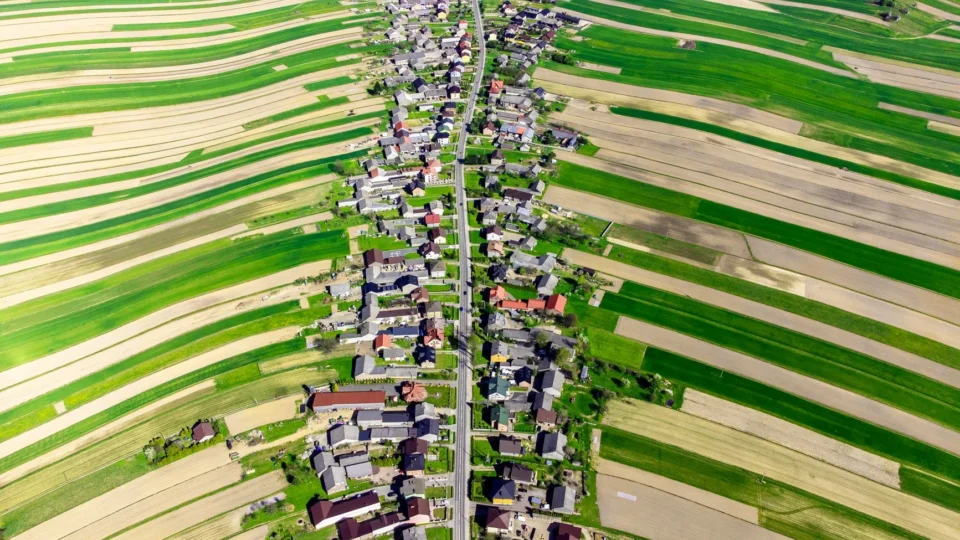 Stunning aerial view of a vibrant Polish village surrounded by lush fields in spring.