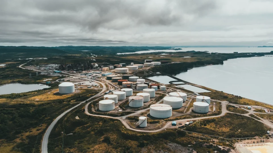 Aerial shot of industrial storage tanks near a waterfront landscape, showcasing industrial infrastructure.