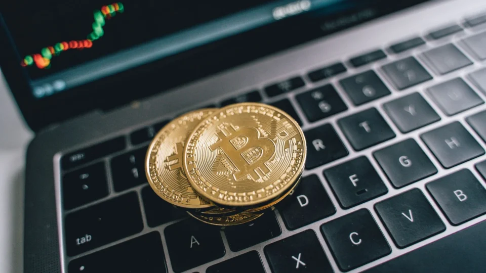 Close-up of golden bitcoins on a laptop keyboard depicting cryptocurrency and trade concepts with a market chart in the background.