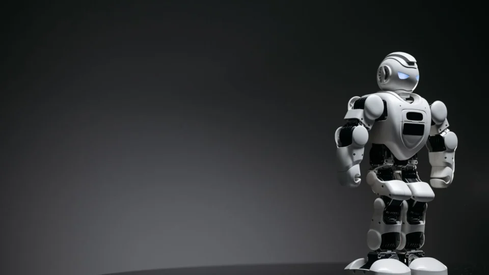 Compact humanoid robot toy standing on a reflective surface, exuding a futuristic vibe.