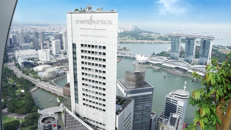 A stunning aerial view of Singapore featuring One Raffles Place and Marina Bay Sands under a clear sky.