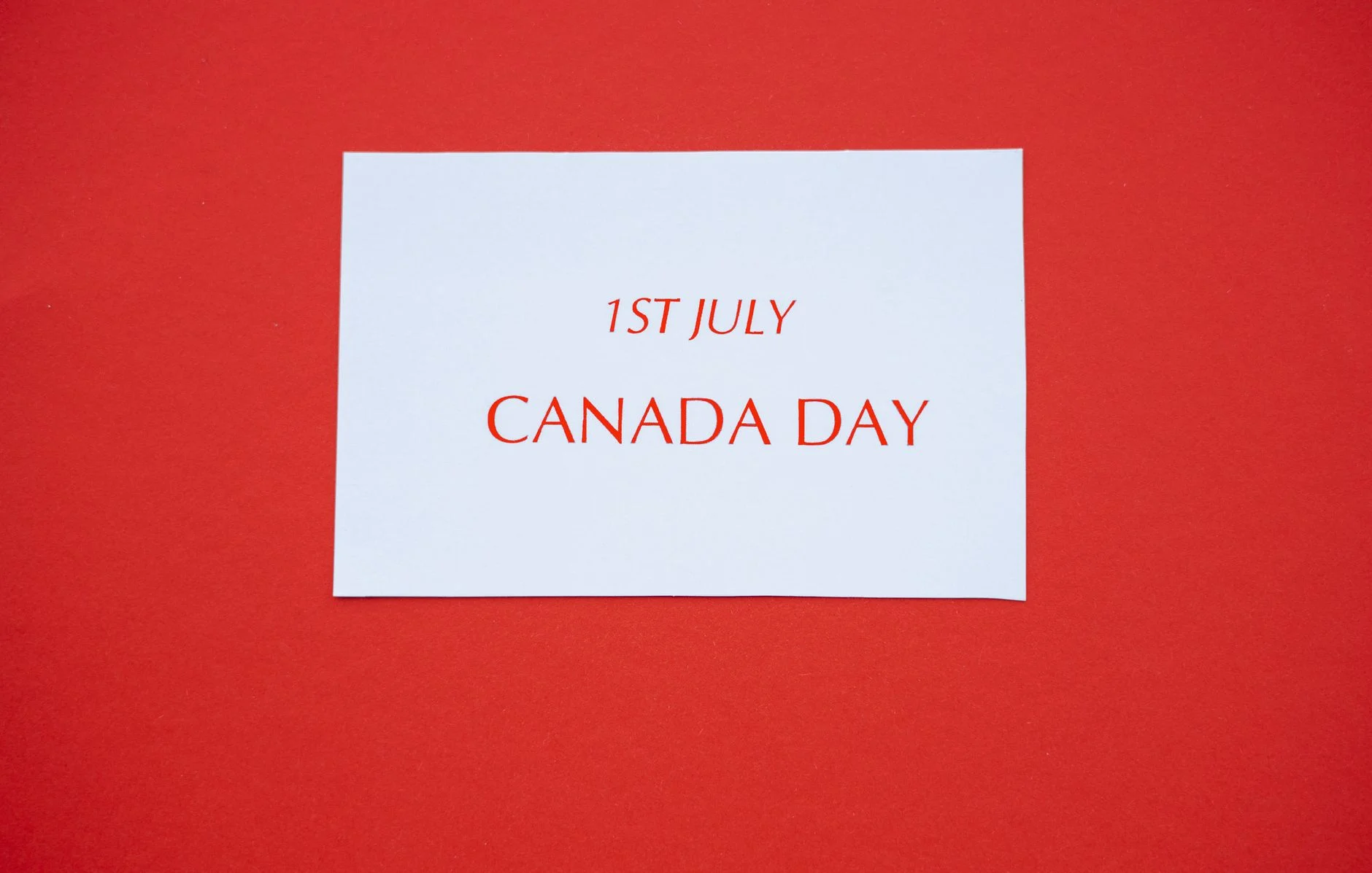 A white card with red text displaying '1st July Canada Day' on a red background.
