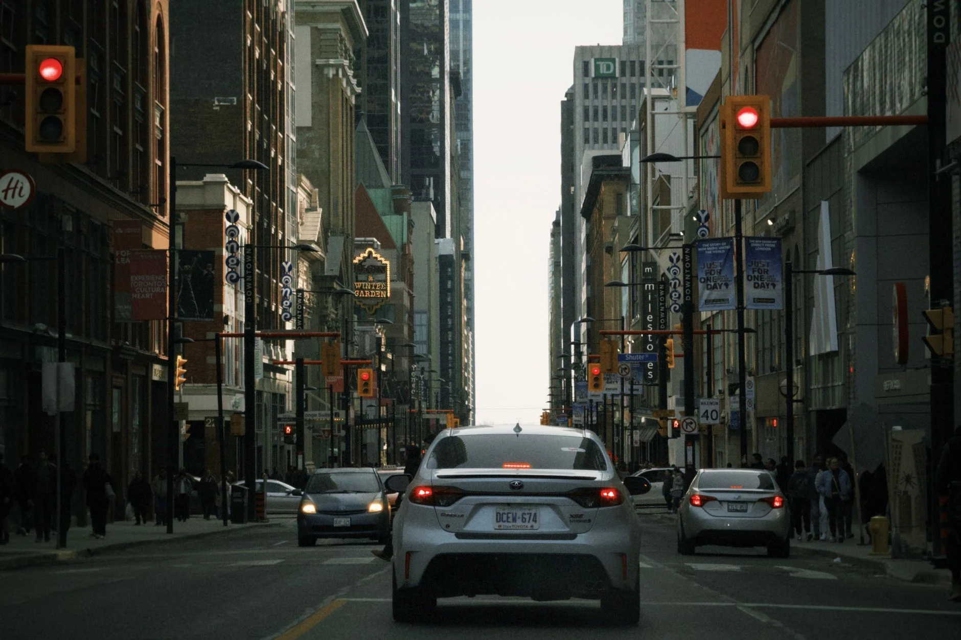 A bustling street view of downtown Toronto with cars and urban buildings in the background.