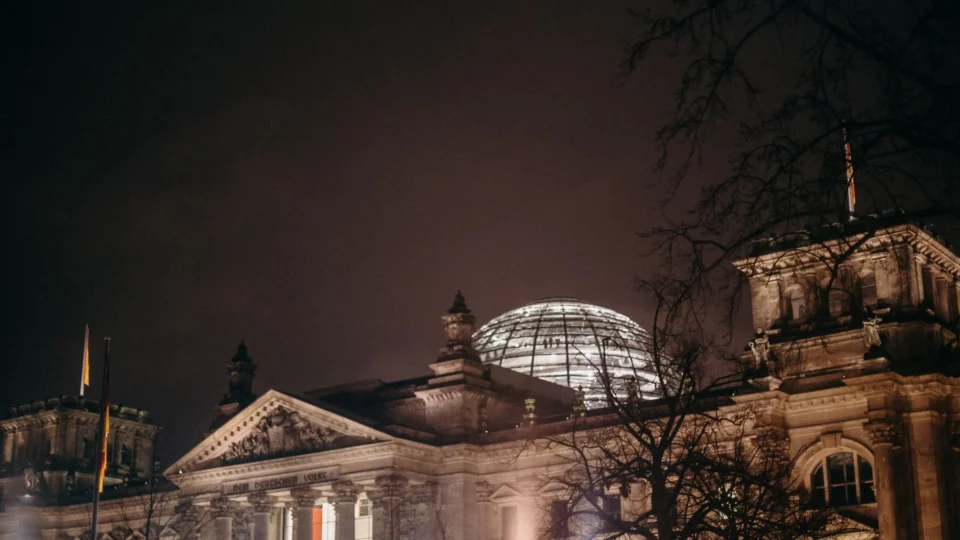Illuminated Reichstag building at night, showcasing its iconic glass dome in Berlin, Germany.