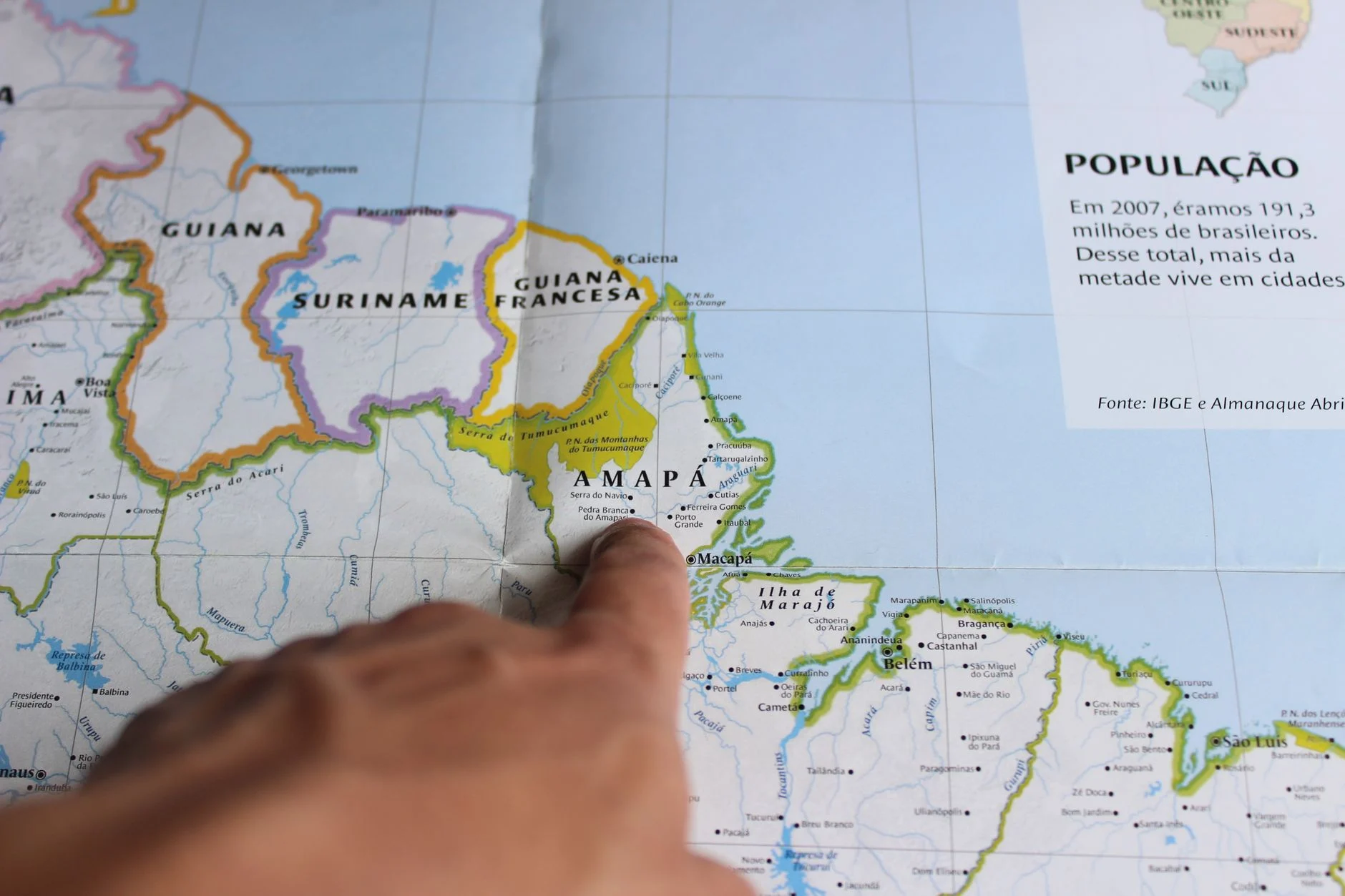 Close-up of a finger pointing at Amapá on a map of Brazil, highlighting geography.