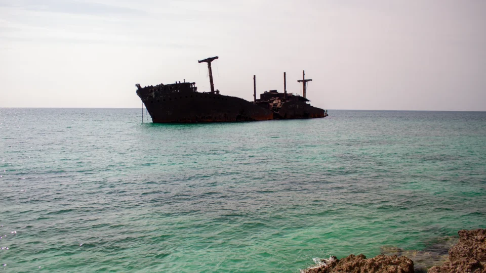Rusty shipwreck in clear turquoise waters off Kish Island, Iran.