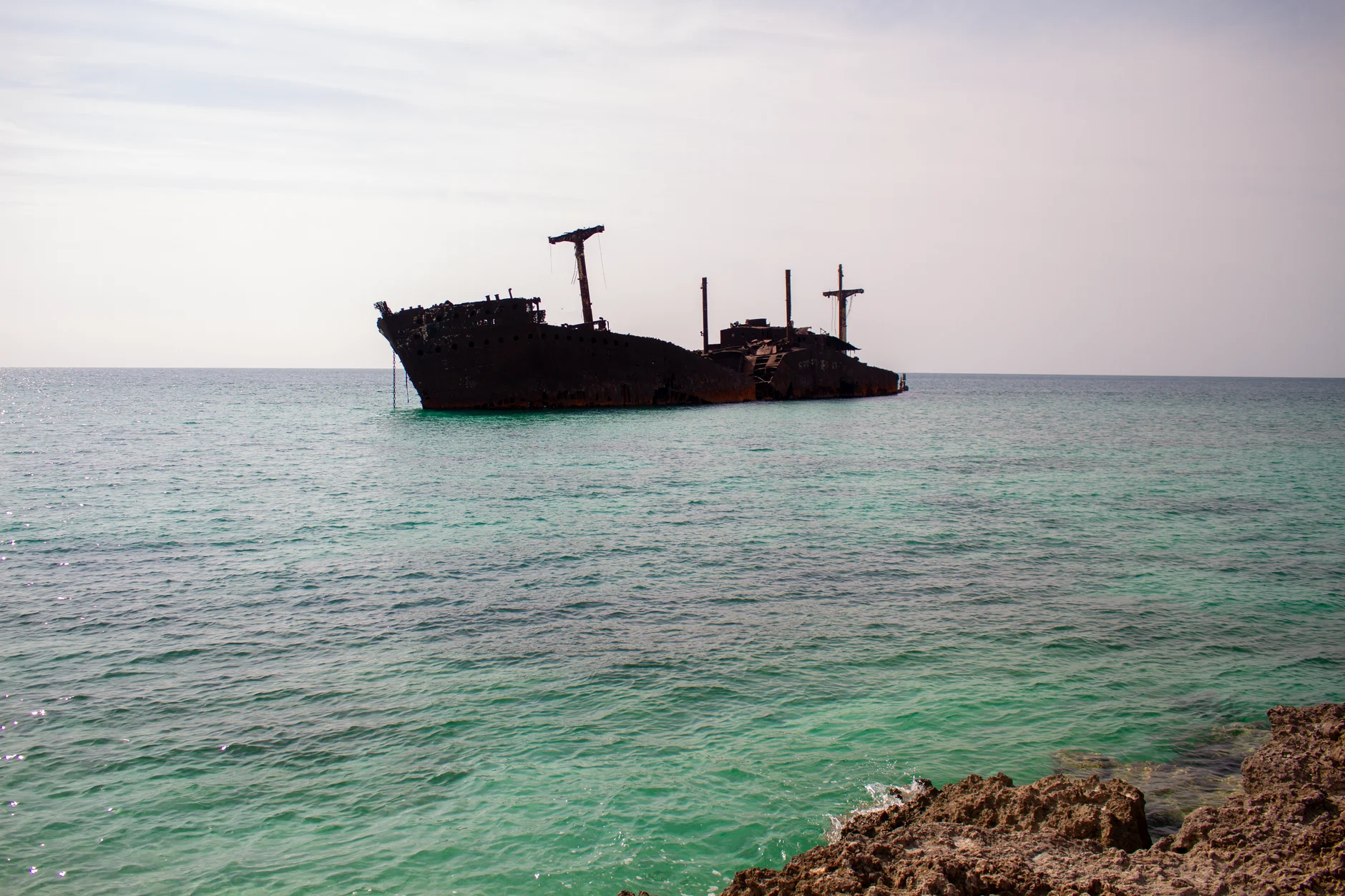 Rusty shipwreck in clear turquoise waters off Kish Island, Iran.