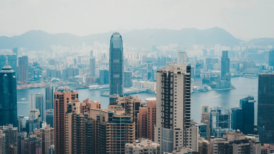 A cityscape of Hong Kong featuring skyscrapers and Victoria Harbor.