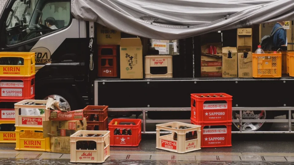 Stacked crates of Japanese beer bottles on a delivery truck in city street.