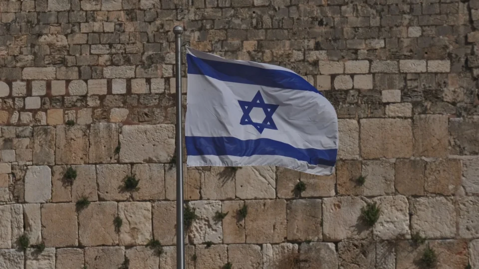 Israeli national flag waving at the historic Western Wall in Jerusalem.