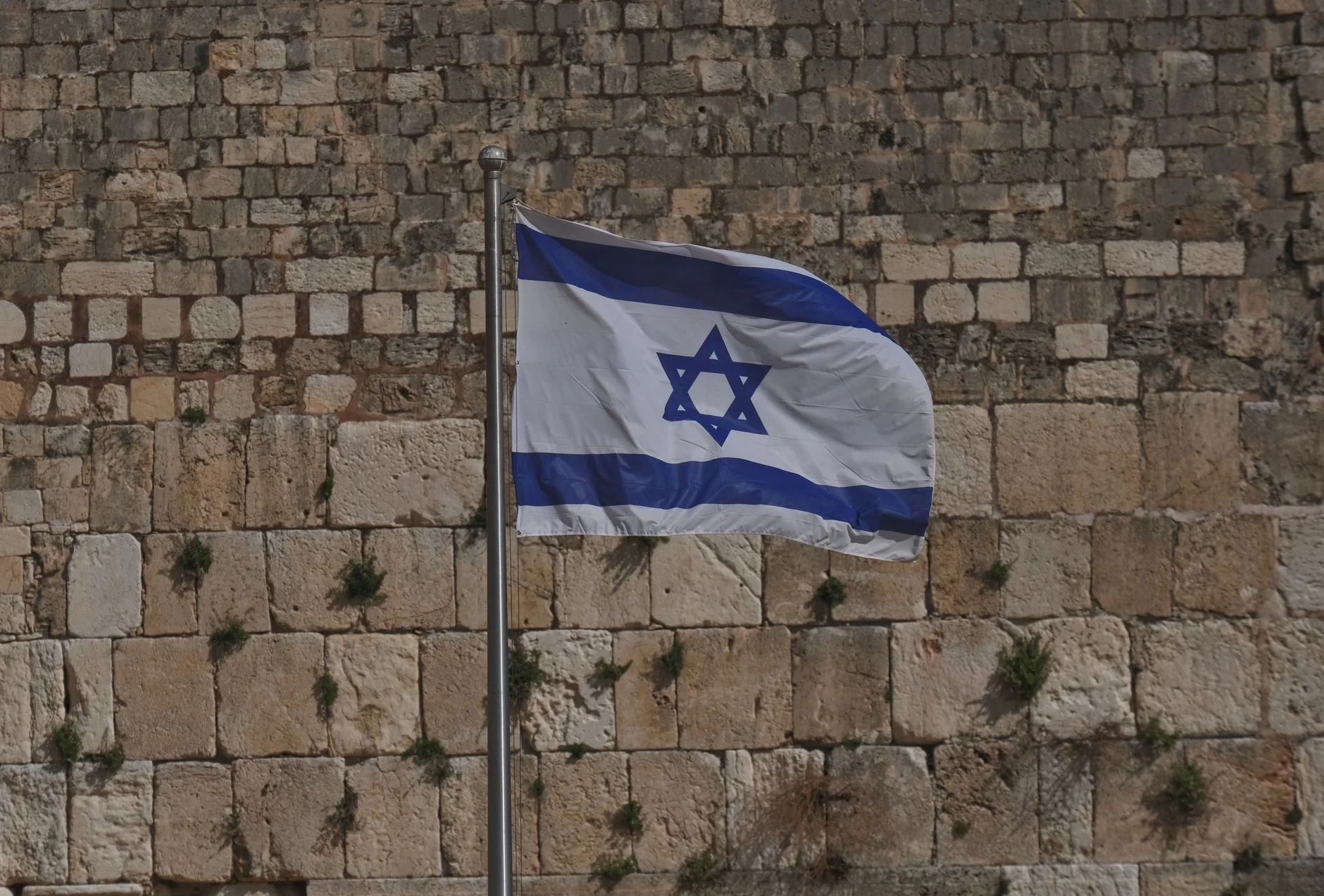 Israeli national flag waving at the historic Western Wall in Jerusalem.