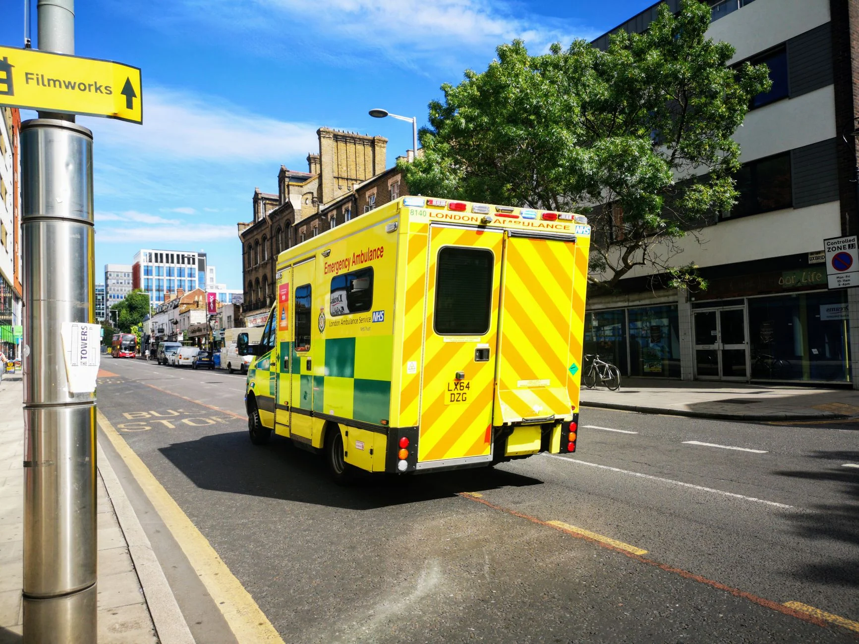 A London emergency ambulance driving through a city street in England, showcasing public health service.