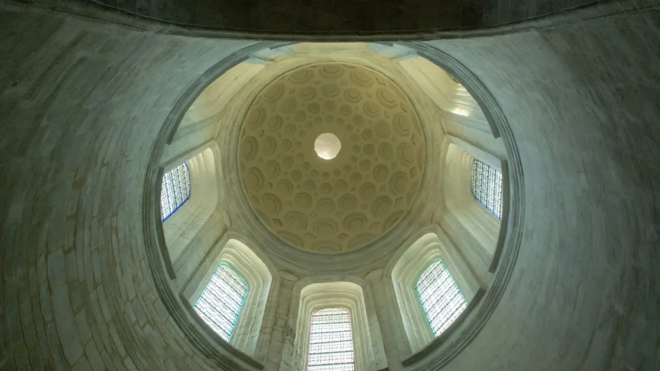 An interior view of the Saint Pierre Cathedral dome with stained glass windows.