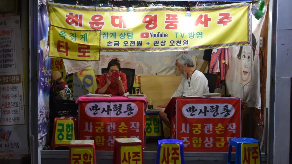 A bustling fortune telling stall in Busan, South Korea, showcasing the local street market culture at night.