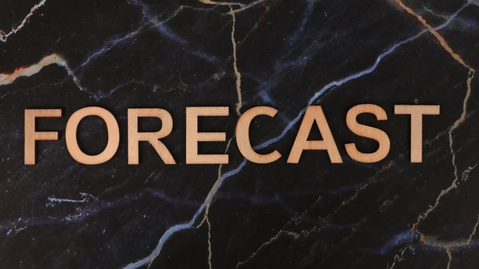 The word 'FORECAST' in wooden letters on a dark marble background.
