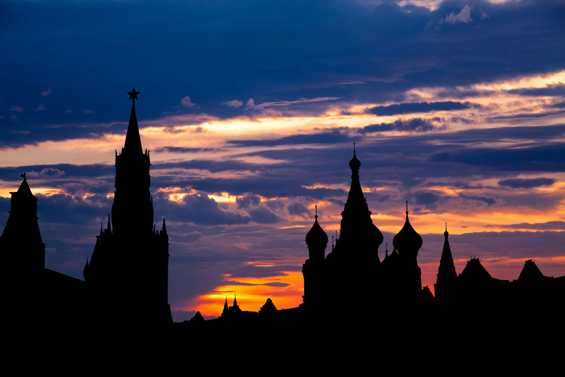Stunning silhouette of the Kremlin towers against a vibrant sunset sky in Moscow, Russia.