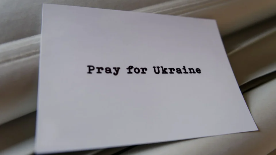 A card message expressing support and prayer for Ukraine on a textured background.