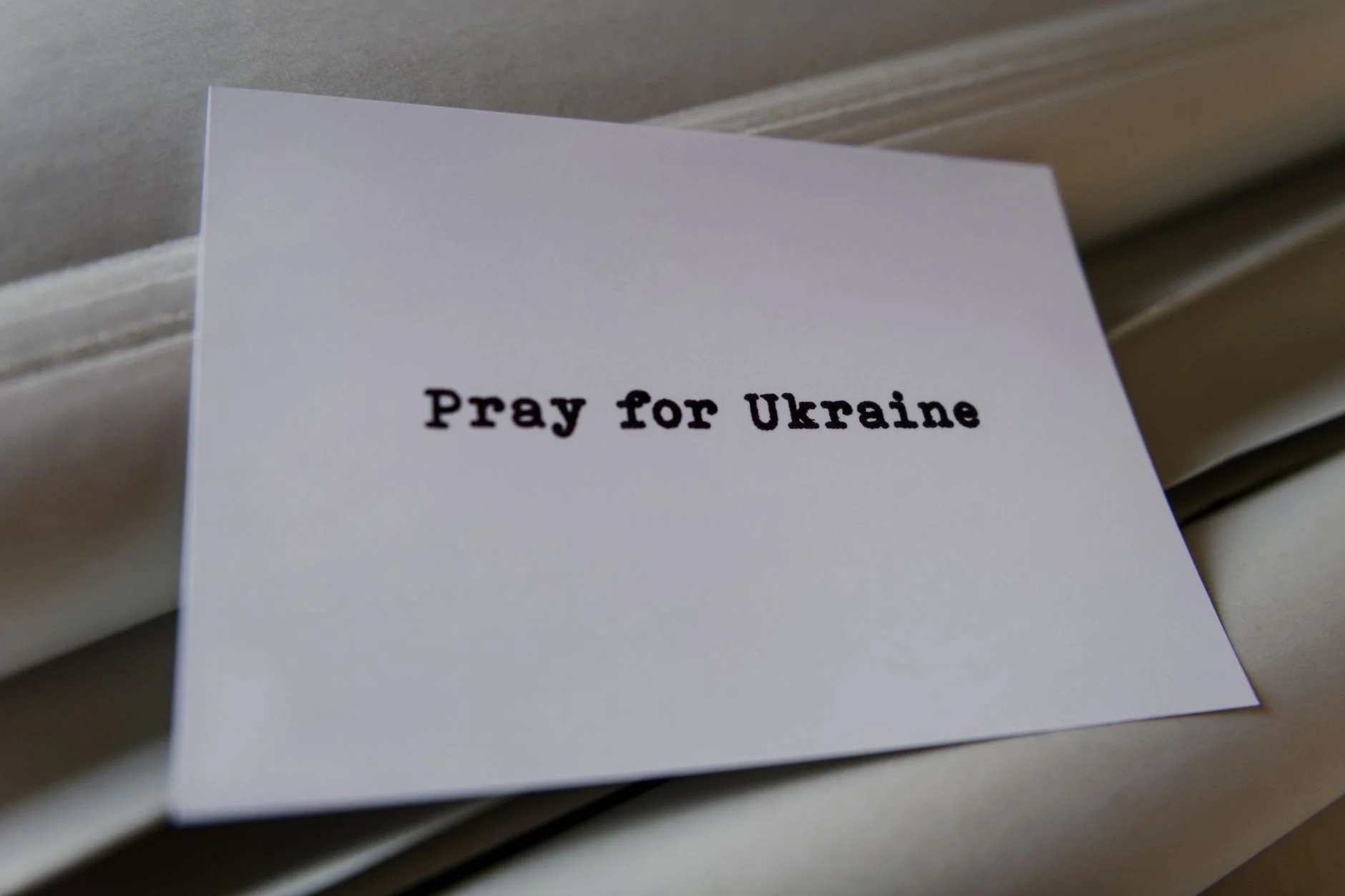 A card message expressing support and prayer for Ukraine on a textured background.