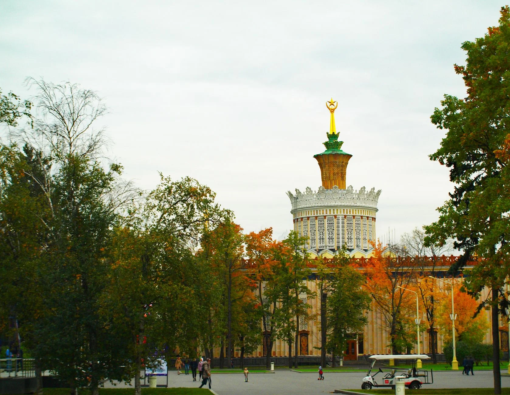 View of Pavilion Ukraine at the All-Russian Exhibition Center with autumn trees and people walking