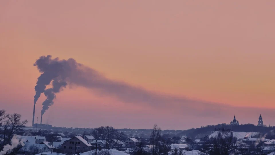 Aerial view of Chernihiv, Ukraine, with chimneys emitting smoke at sunset in winter.