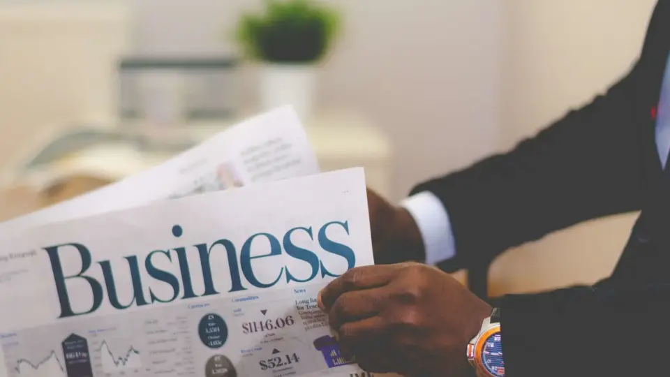 Close-up of a businessman reading a newspaper indoors, focusing on business headlines.