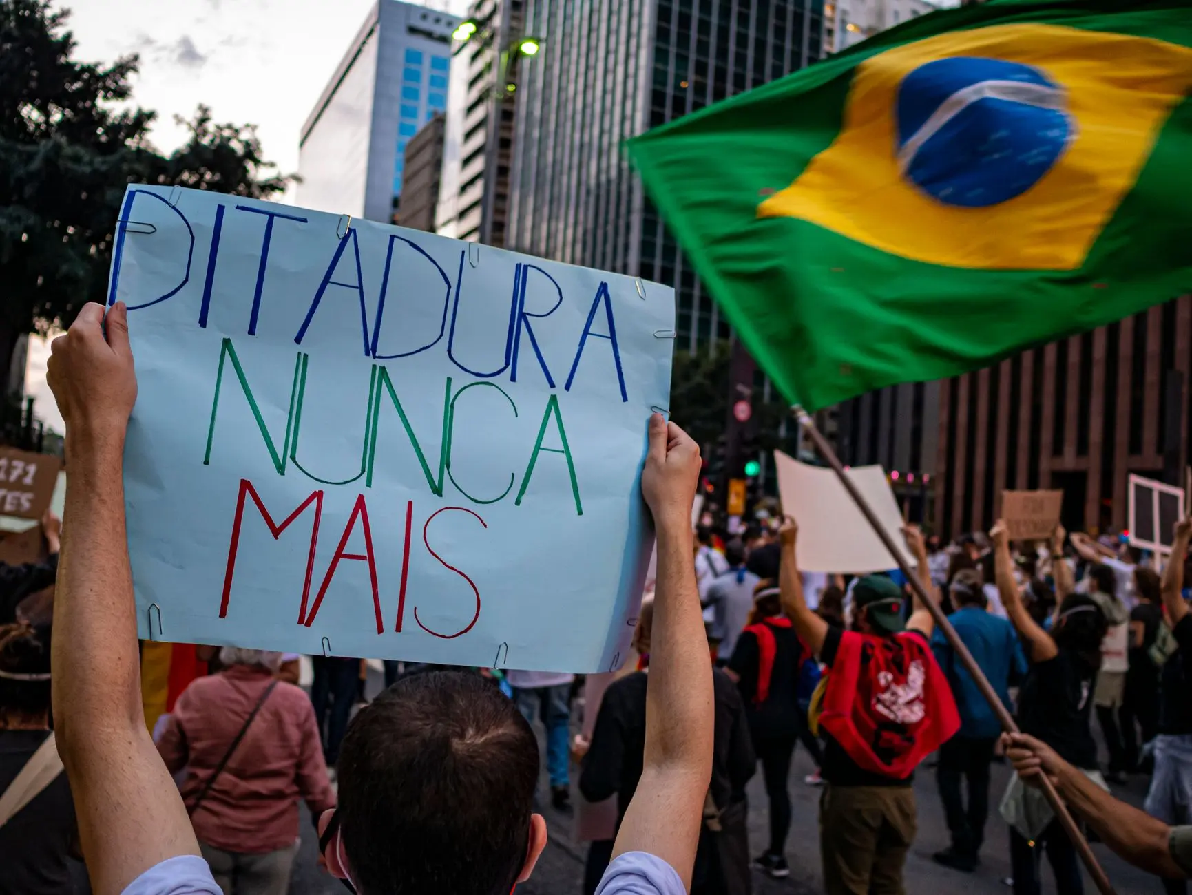 Protesters rally in São Paulo, Brazil, holding signs for human rights and democracy.