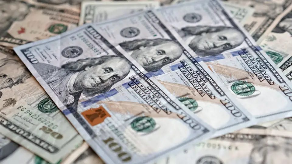 A detailed close-up of multiple U.S. dollar banknotes arranged in a scattered layout.