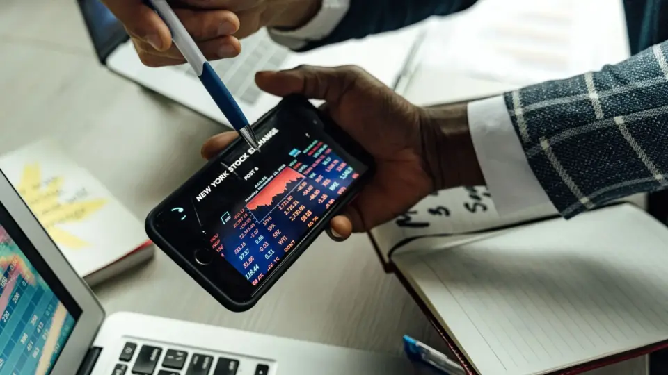 Business professionals analyzing stock exchange data on a smartphone in an office setting.