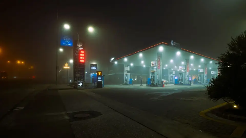 A foggy night view of a well-lit gas station in Jordan, providing an atmospheric urban scene.