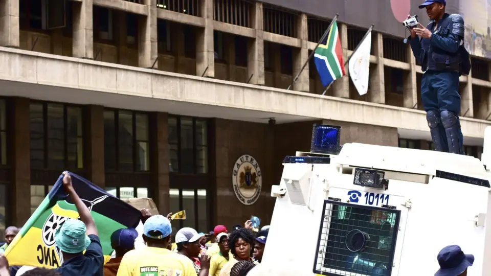 A protest with a police officer photographing the crowd in urban South Africa.