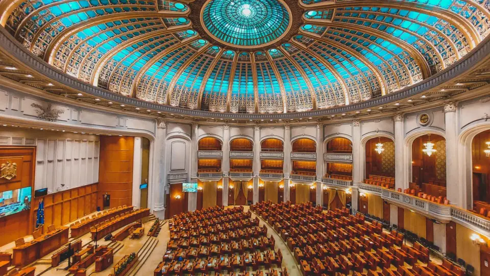 Vibrant interior of a parliament hall with a grand dome and intricate architecture.