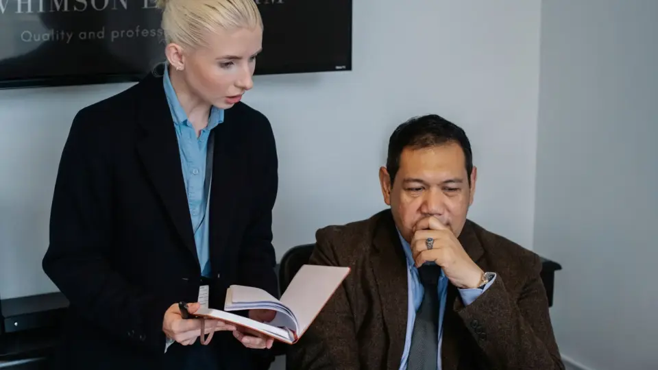 Serious multiracial coworkers in formal clothes gathering together and discussing details of business project while working in office