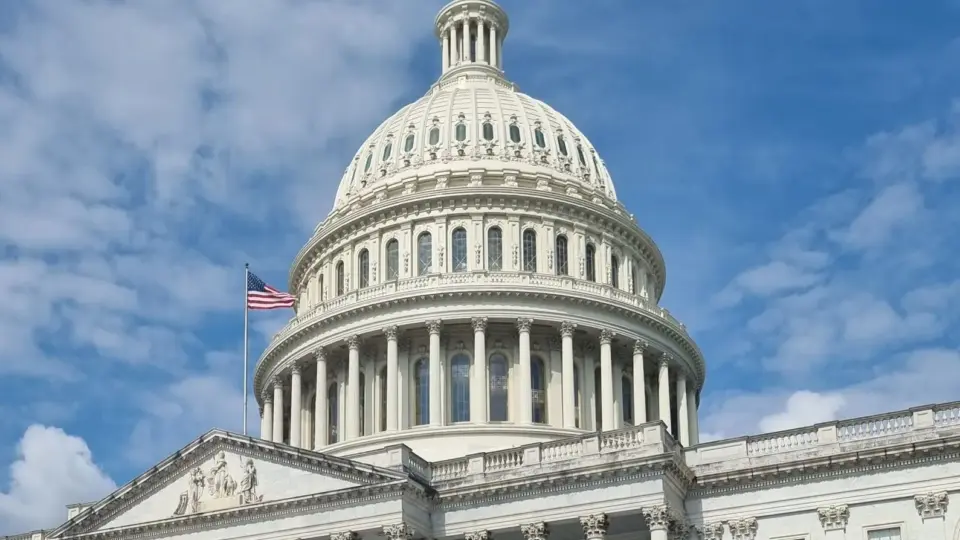 A striking view of the US Capitol dome with flag and blue sky in Washington, DC.